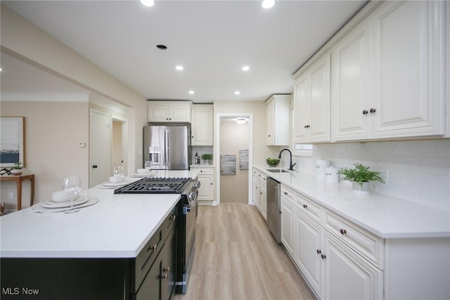 6544 Nancy Dr, North Olmsted, OH 44070 - kitchen with a sink, stainless steel appliances, light wood-type flooring, white cabinetry, and a center island