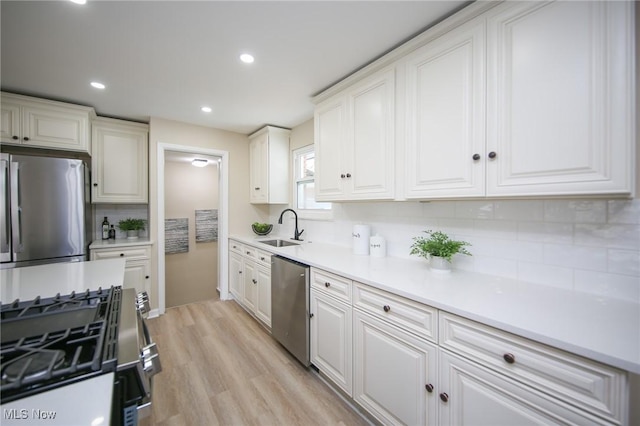 6544 Nancy Dr, North Olmsted, OH 44070 - kitchen featuring a sink, light wood finished floors, backsplash, white cabinetry, and appliances with stainless steel finishes