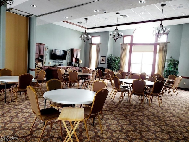 carpeted dining room with a paneled ceiling, visible vents, and a notable chandelier