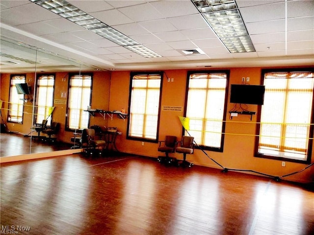 interior space featuring a drop ceiling, visible vents, wood finished floors, and baseboards