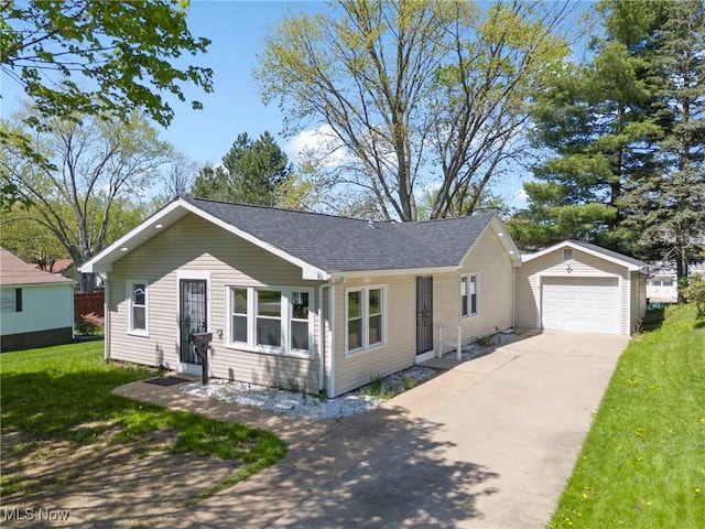view of front of property featuring driveway, a garage, an outbuilding, a front lawn, and a shingled roof