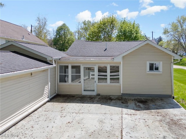 rear view of property featuring roof with shingles, a sunroom, and a patio