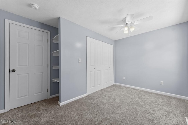 unfurnished bedroom with ceiling fan, carpet floors, a closet, and baseboards