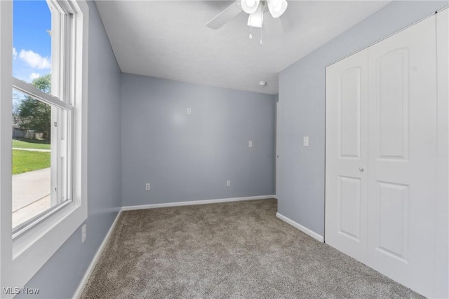 unfurnished bedroom with carpet flooring, baseboards, a closet, and a ceiling fan