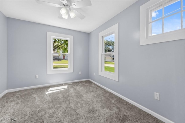 carpeted spare room featuring plenty of natural light, baseboards, and a ceiling fan