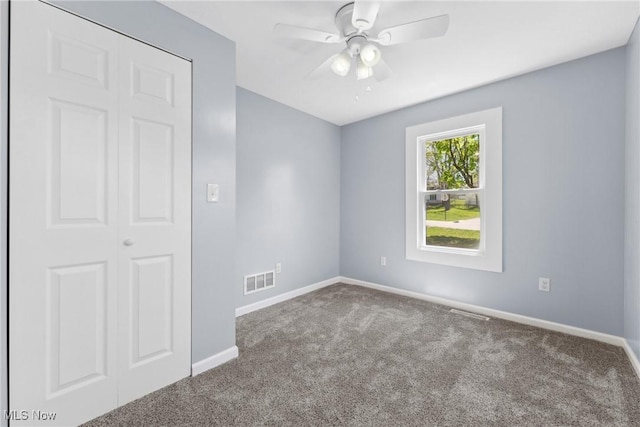 spare room with a ceiling fan, carpet floors, baseboards, and visible vents