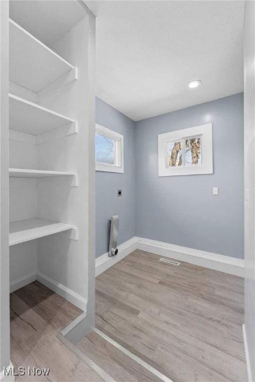 laundry area featuring wood finished floors, electric dryer hookup, laundry area, baseboards, and recessed lighting