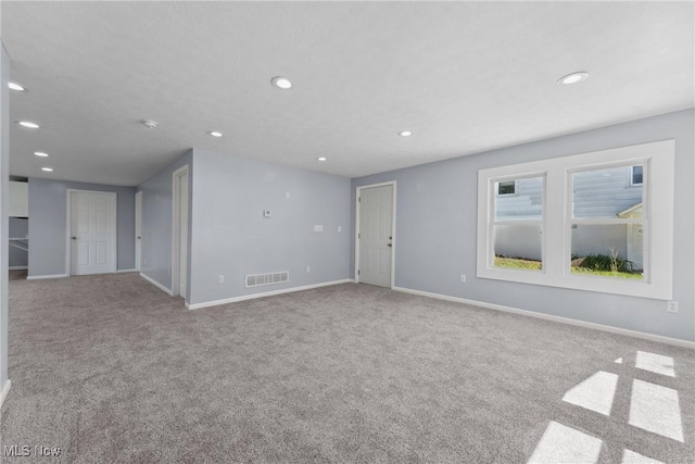 carpeted empty room featuring baseboards, visible vents, and recessed lighting
