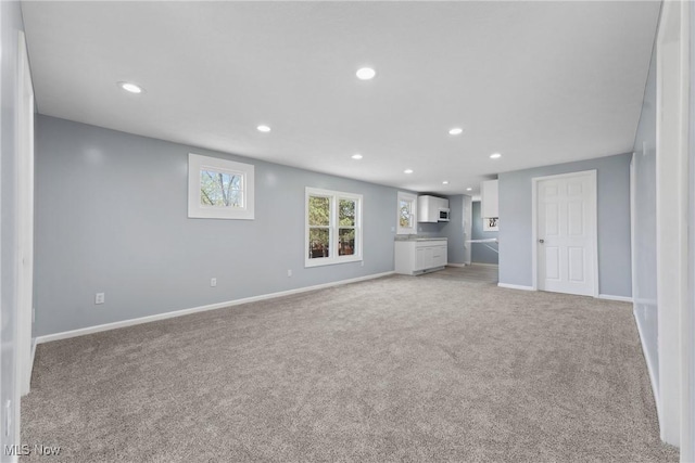 unfurnished living room with light colored carpet, baseboards, and recessed lighting