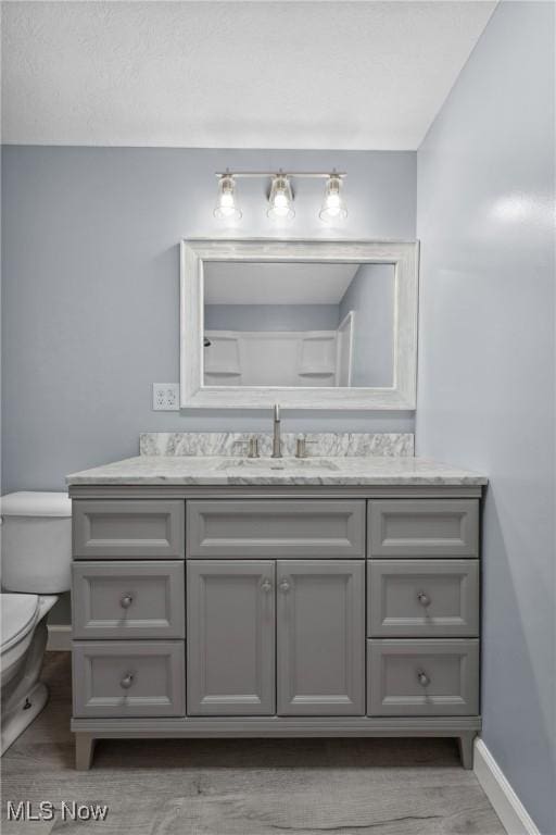 bathroom featuring toilet, baseboards, and vanity