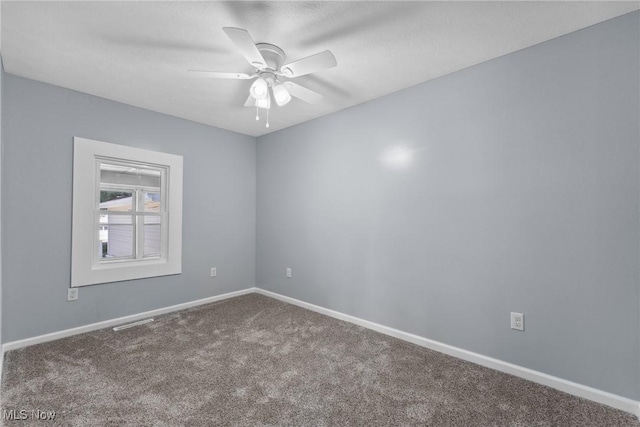 carpeted spare room with visible vents, baseboards, and ceiling fan