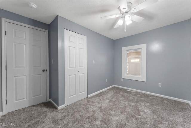 unfurnished bedroom with a closet, baseboards, ceiling fan, and carpet floors