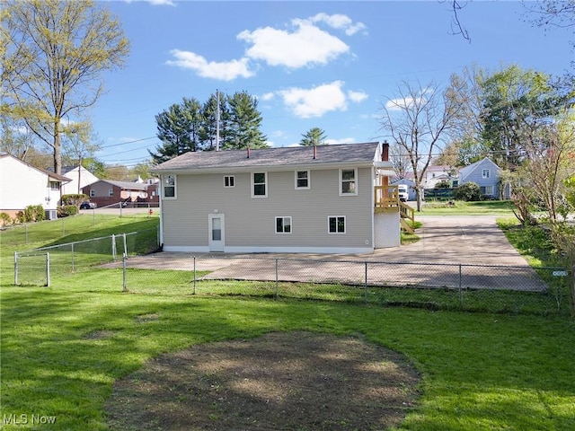 rear view of property featuring a yard, fence, and a chimney