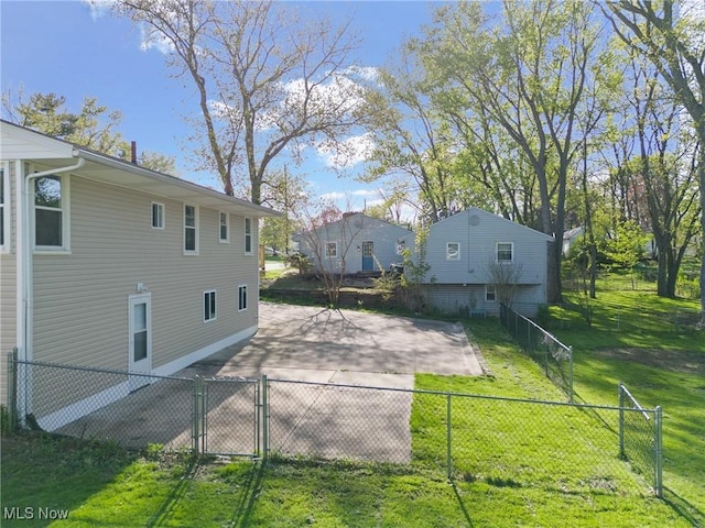 exterior space with a gate, fence, and a lawn