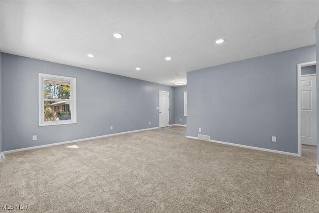 carpeted empty room with baseboards, visible vents, and recessed lighting