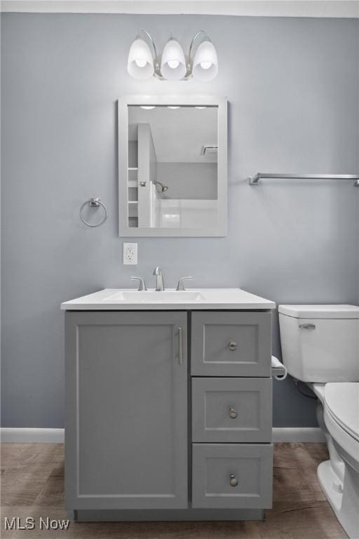 bathroom featuring toilet, baseboards, and vanity