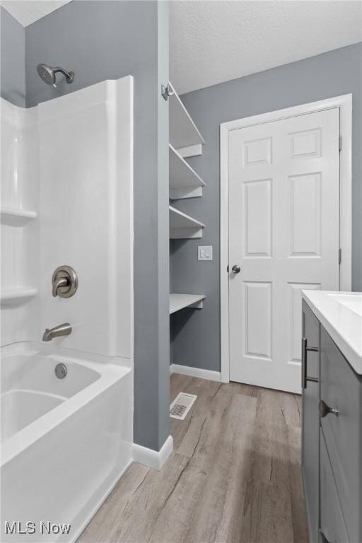 full bathroom with shower / washtub combination, wood finished floors, vanity, visible vents, and baseboards