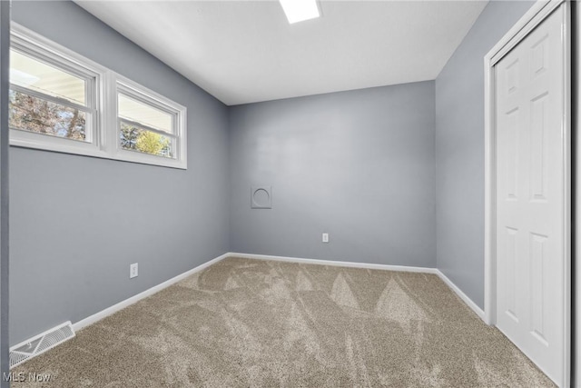 spare room with carpet, visible vents, and baseboards
