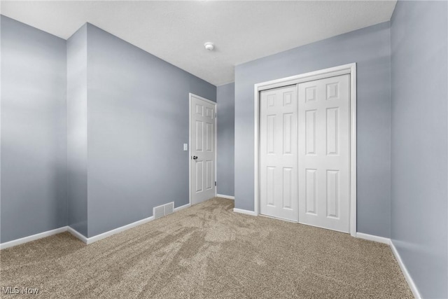 unfurnished bedroom featuring carpet flooring, baseboards, a closet, and visible vents