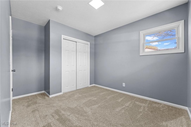 unfurnished bedroom with carpet flooring, a closet, and baseboards