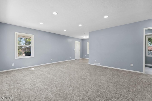 carpeted empty room with baseboards, visible vents, and recessed lighting