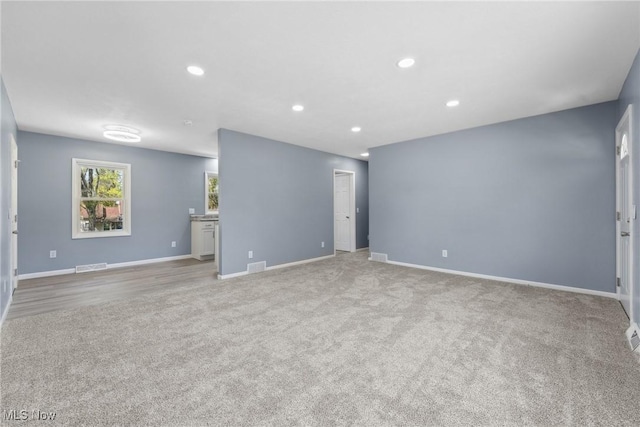 unfurnished living room with light colored carpet, baseboards, visible vents, and recessed lighting