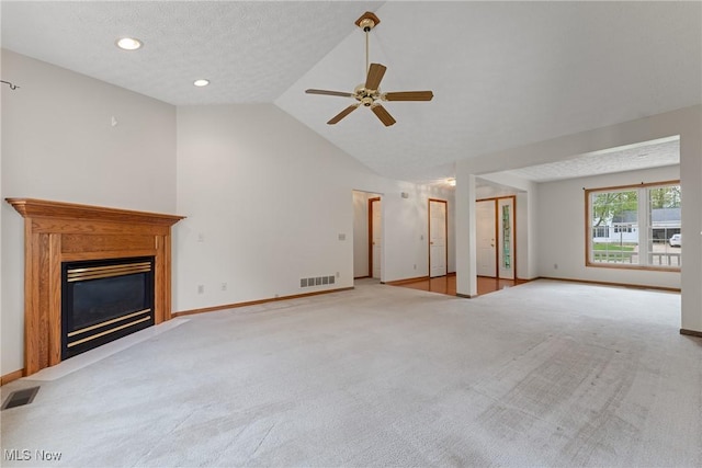 unfurnished living room featuring ceiling fan, a glass covered fireplace, visible vents, and carpet floors