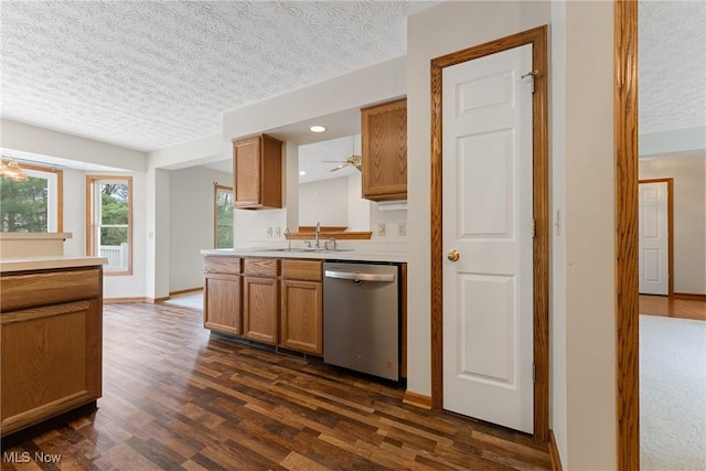 kitchen with a sink, a textured ceiling, dark wood finished floors, dishwasher, and light countertops