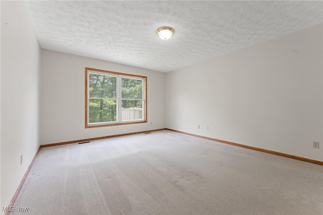 carpeted empty room featuring baseboards and a textured ceiling