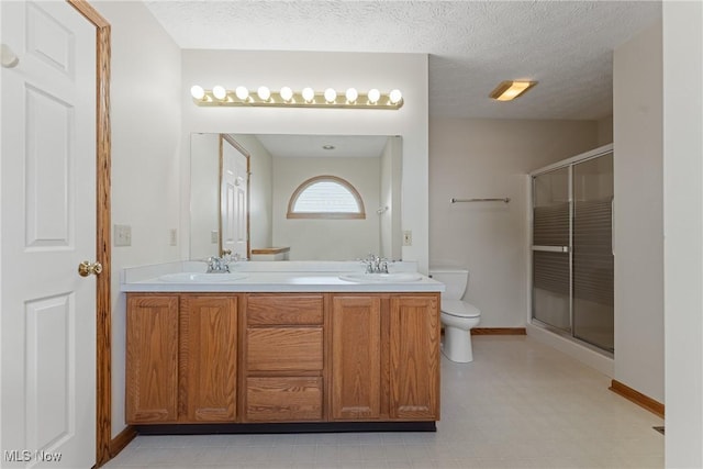full bath featuring a sink, toilet, a stall shower, and baseboards