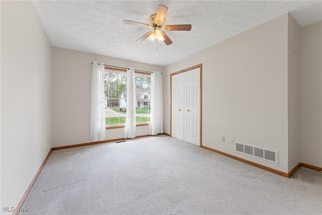 spare room featuring ceiling fan, carpet flooring, baseboards, and visible vents