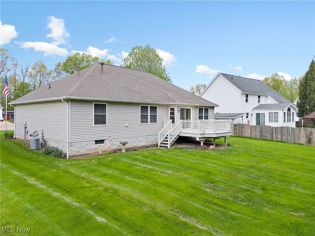 rear view of house with roof with shingles, fence, a yard, a wooden deck, and cooling unit
