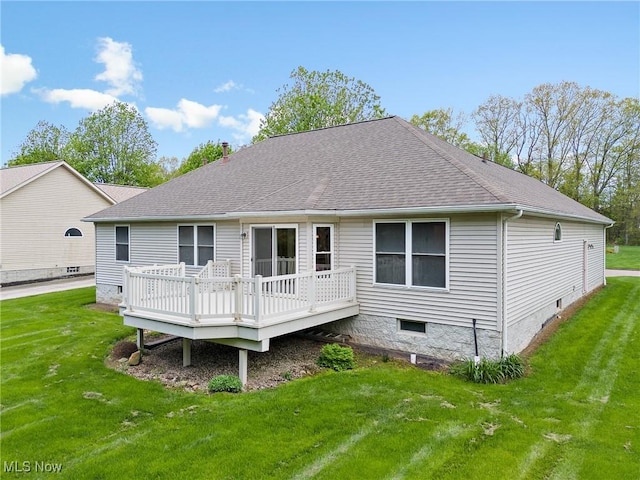 rear view of house featuring a shingled roof, a deck, and a lawn