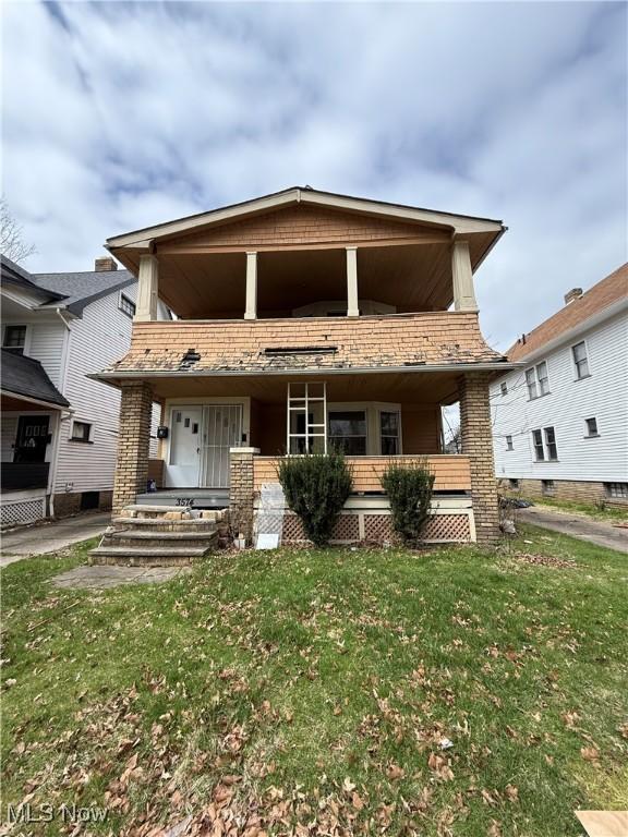 view of front of property featuring covered porch, a front yard, and a balcony