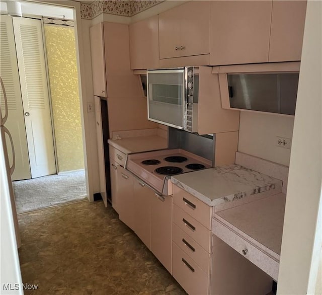 kitchen featuring stainless steel microwave, light countertops, and dark floors