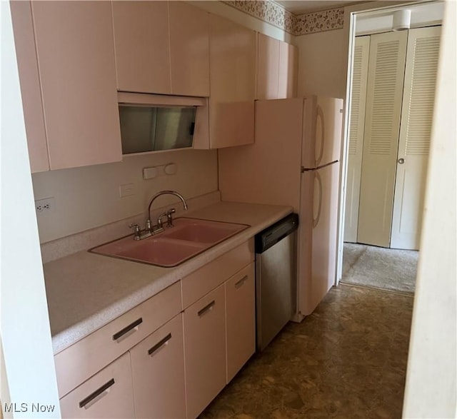 kitchen with dark floors, light countertops, a sink, and dishwasher