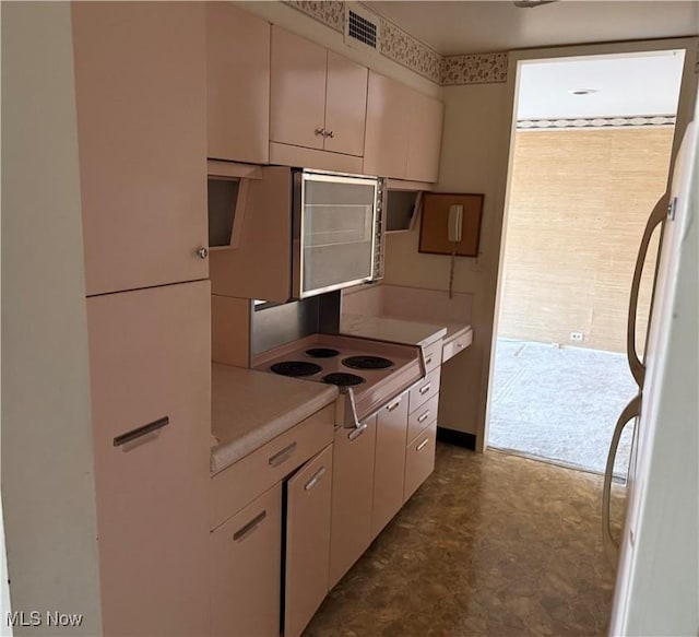 kitchen with freestanding refrigerator, light countertops, visible vents, and dark floors