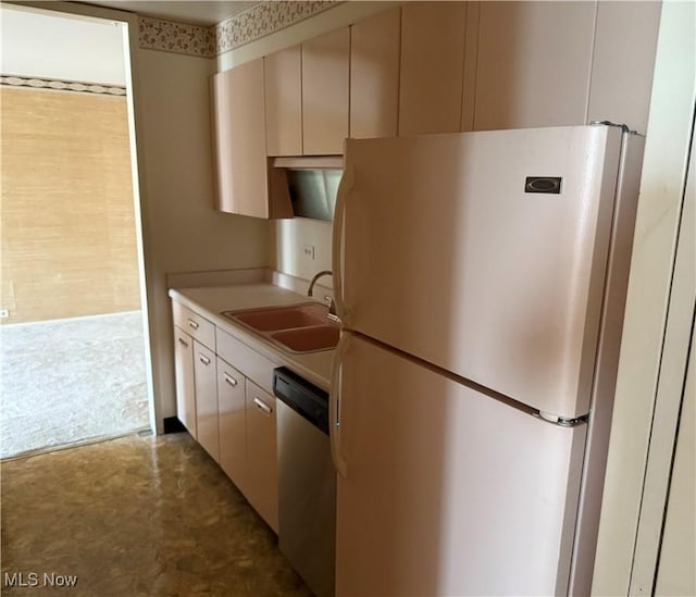 kitchen featuring light countertops, cream cabinets, a sink, freestanding refrigerator, and dishwasher