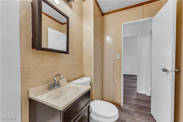half bathroom featuring tile walls, toilet, wood finished floors, and vanity