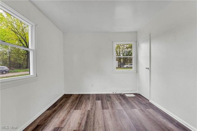 unfurnished room featuring baseboards, plenty of natural light, and dark wood finished floors