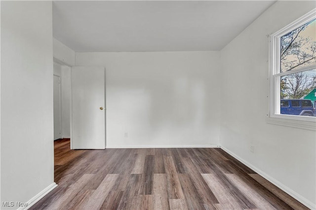 spare room with baseboards and wood finished floors