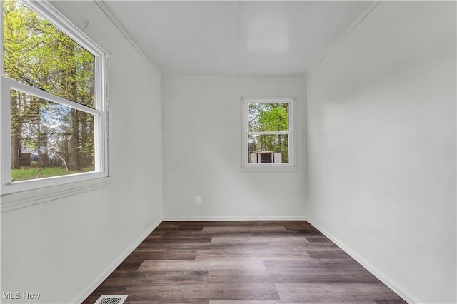 spare room with baseboards, crown molding, and dark wood-type flooring