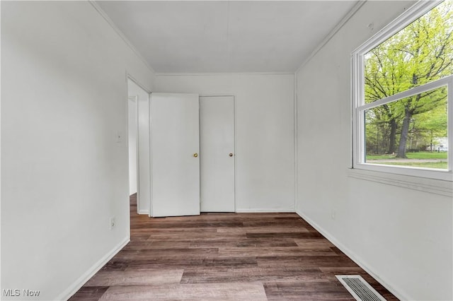 unfurnished bedroom with visible vents, wood finished floors, and ornamental molding
