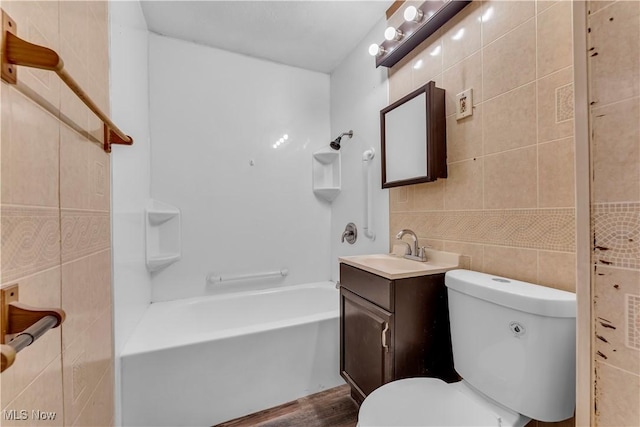 bathroom featuring shower / bathing tub combination, vanity, tile walls, and toilet