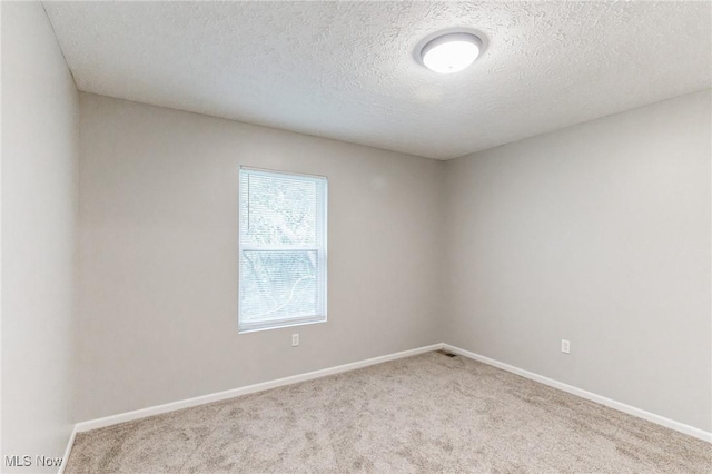 unfurnished room featuring a textured ceiling, carpet flooring, and baseboards