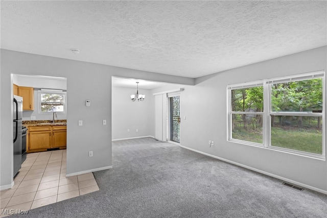 unfurnished living room with a sink, a notable chandelier, baseboards, and visible vents