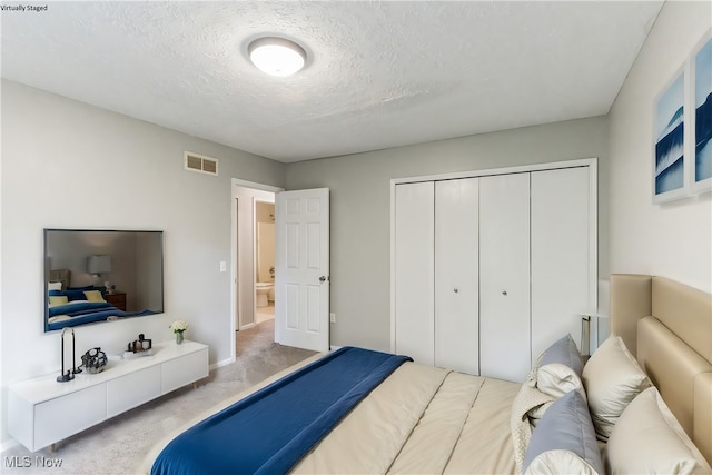 bedroom featuring a closet, a textured ceiling, baseboards, carpet flooring, and visible vents