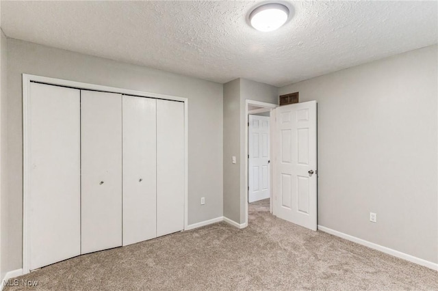 unfurnished bedroom with a textured ceiling, baseboards, a closet, and carpet floors