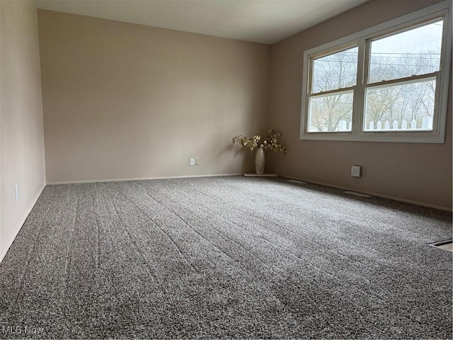 carpeted empty room featuring baseboards