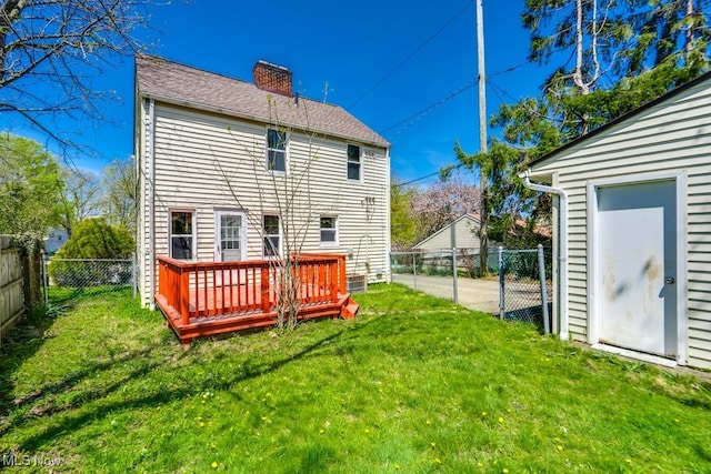 rear view of house featuring a lawn, a chimney, a wooden deck, and a fenced backyard